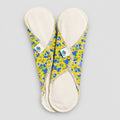 Deux serviettes hygiéniques entretien facile dessus blanc et dessous jaune et fleurs bleues.